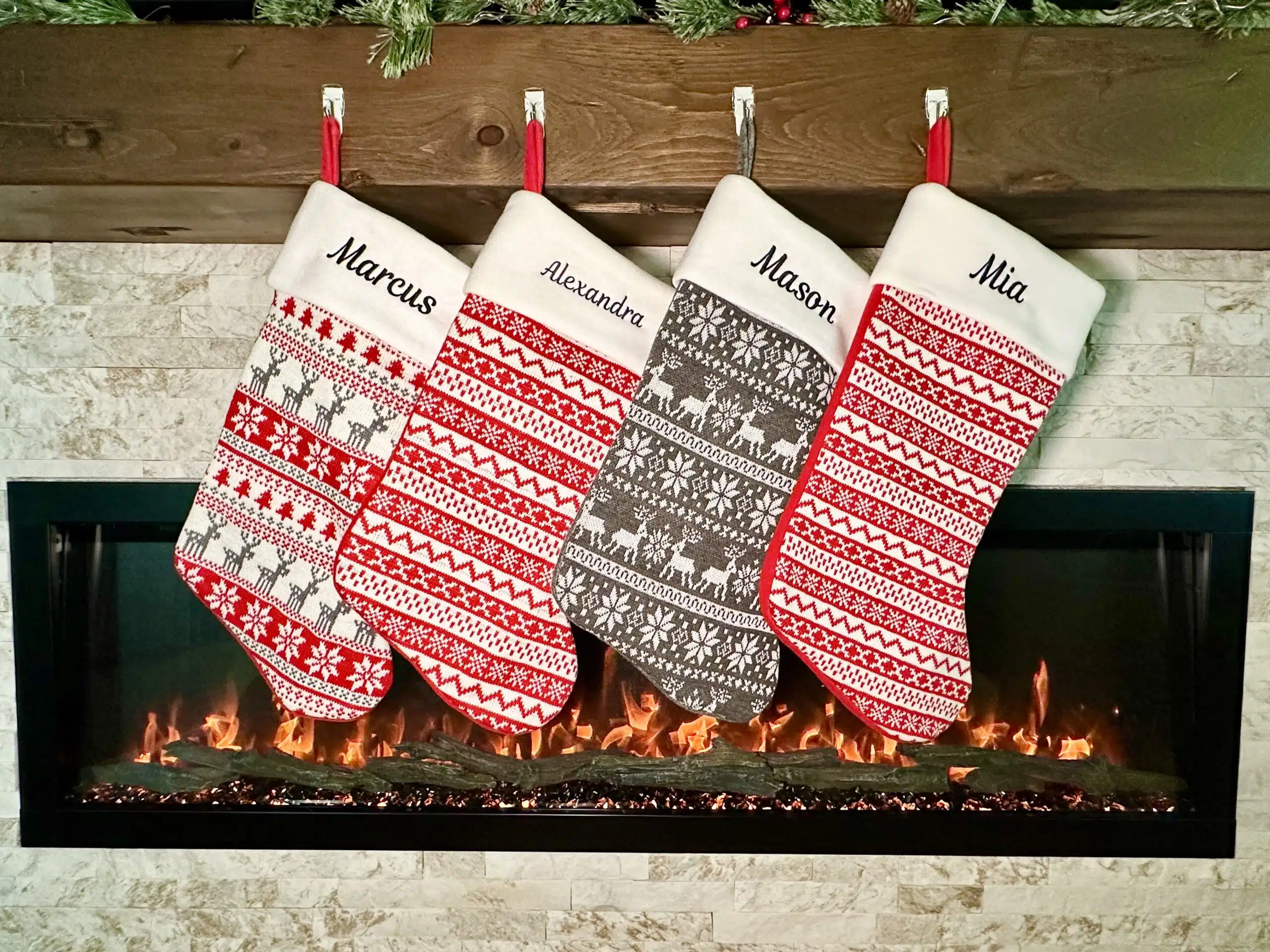 Personalised Christmas stockings in red, green and white hanging on a mantel with embroidered names